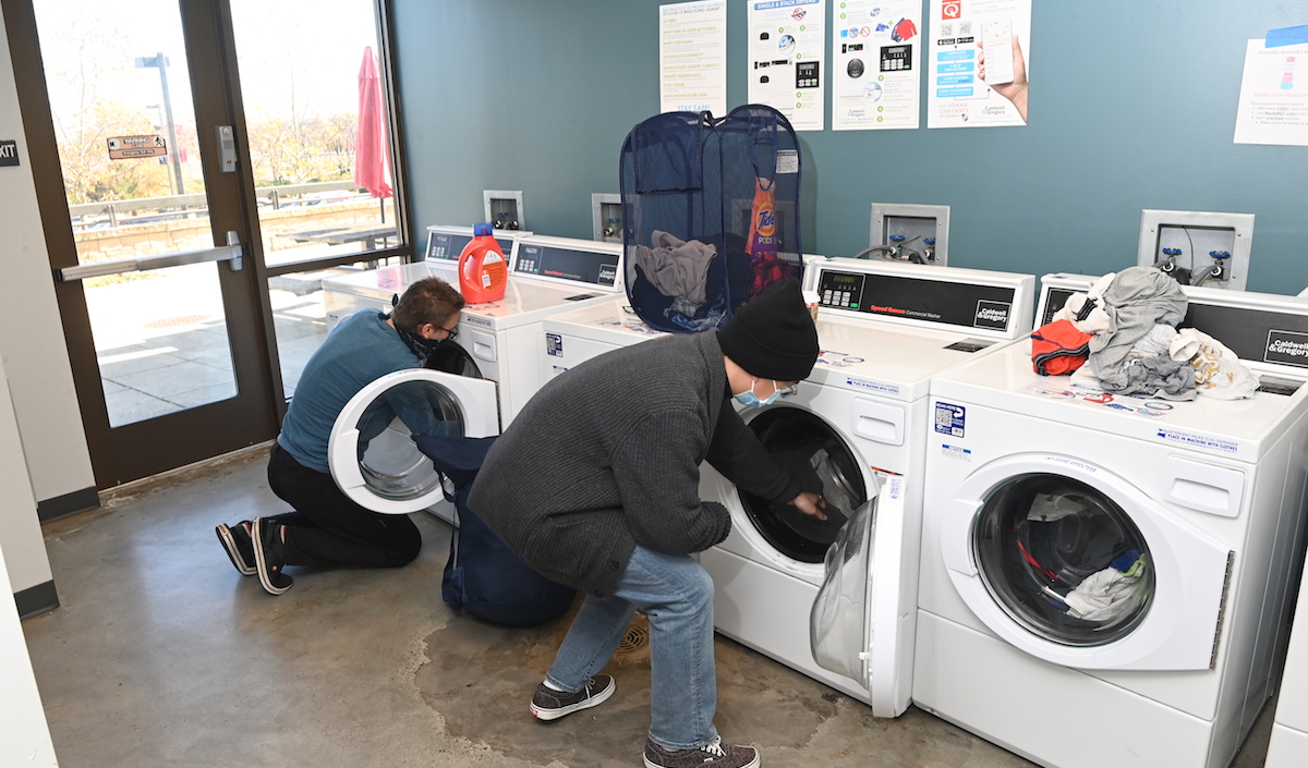 Residents of Millennium North put their laundry in the residence hall's washing machines in its communal laundry room