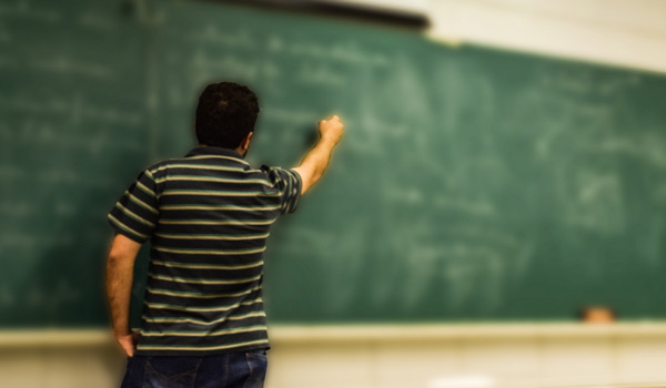 A student solving math problems on a chalkboard.