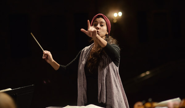 A student conducts a performance of Carnival of Animals on stage.