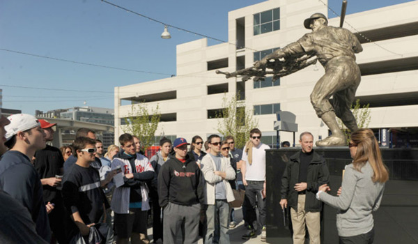 A 蜜桃社 class standing next to a baseball statue on a class outing.