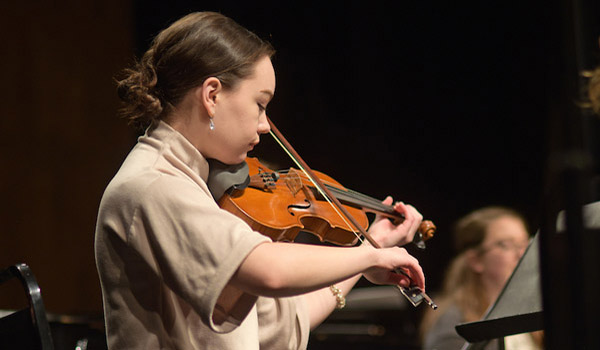 A student performs the violin on stage.
